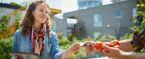 Merchant at a farmers' market accepting a secured credit card from a customer after learning how they work