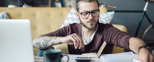 Young man with books and a laptop open, trying to learn about credit card interest