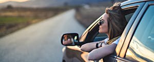 A woman in a car at sunset contemplates her potential auto refinancing savings A woman in a car at sunset contemplates her potential auto refinancing savings