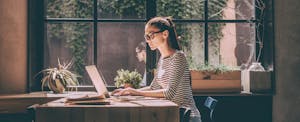 Young woman on laptop, learning about the three credit bureaus