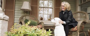 Senior woman sitting on porch rocking chair with dog