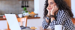 Worried young woman sitting at home thinking about how to pay off student loans.