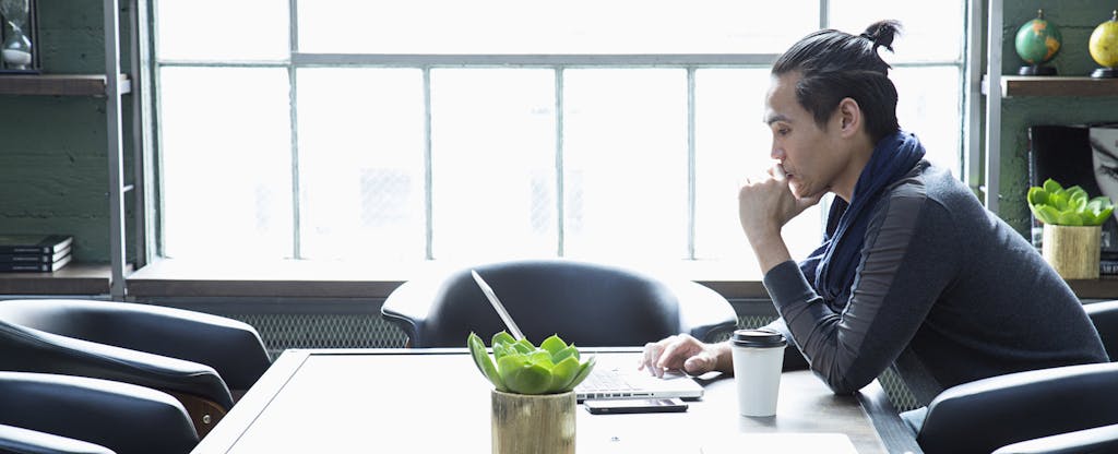 Businessman using laptop in a modern office, looking serious