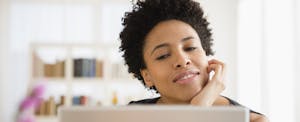 Woman using laptop considers balance transfer pros and cons.