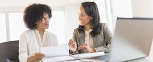 Women conferring at desk with laptop