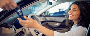 Woman sits in her new car as the deal hands her the keys