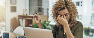 Stressed young woman using a computer at her work desk