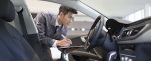 car-appraisal Man looking at a car and taking notes on a clipboard