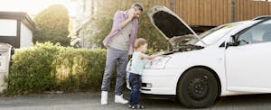 lemon-laws Man talking on the phone while standing outside of his broken-down car with his son