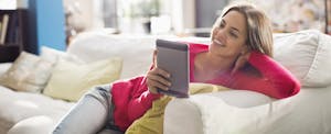 online-title-loans Woman using digital tablet on sofa