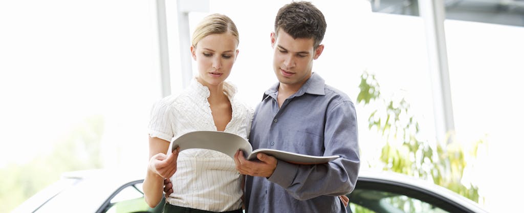 Couple at a car dealership looking through paperwork