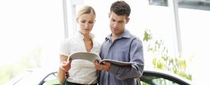 Couple at a car dealership looking through paperwork