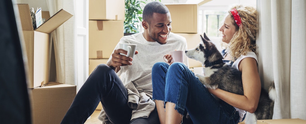Couple playing with their dog as they unpack boxes in their new home