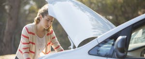 how-to-sell-car-for-parts Woman looking under the hood of her car