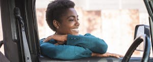 nissan-motor-acceptance-corp_722209135 Smiling African American woman leaning on car window