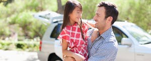 what-is-a-lease-acquisition-fee Father holding daughter outdoors with car in background