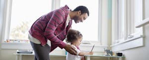 Happy father assisting daughter with homework