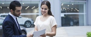 Woman doing a car title transfer at car dealership