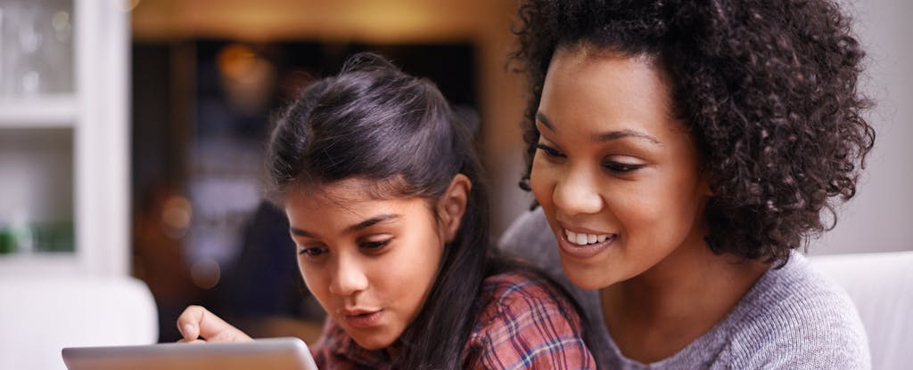 Woman looking at a tablet with her young daughter, smiling