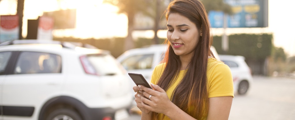 Woman on cell phone looking up a free Carfax report