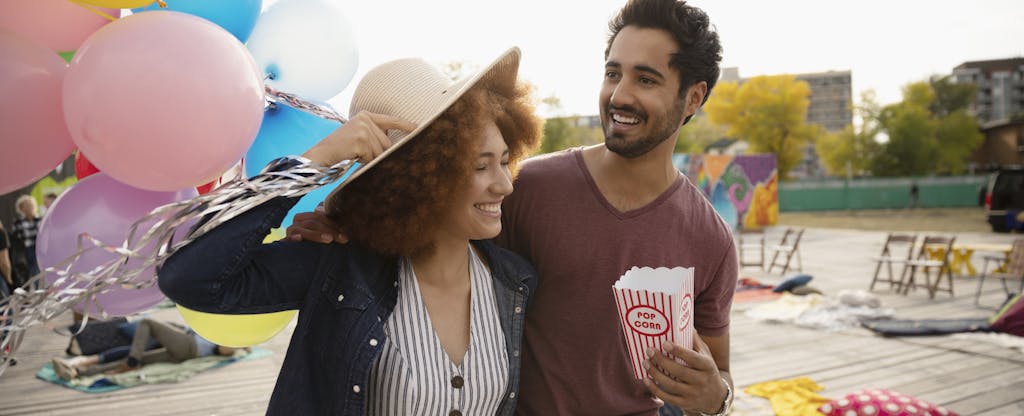 Young couple with popcorn and balloons in urban park