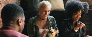 Friends sitting around a table at a restaurant, sharing appetizers and using their dining rewards program to maximize points