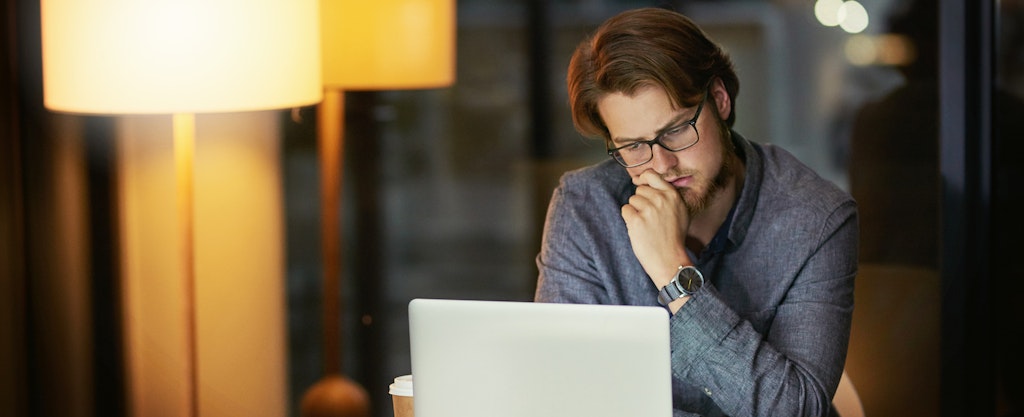 Man using his laptop at home, looking thoughtful as he reads about alternatives to payday loans in PA