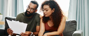 Man and woman sitting together at home on their couch, considering a MaxLend loan