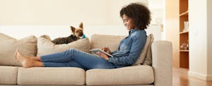 credit-cards-with-trip-cancellation-insurance_494343162 woman on couch cancelling her trip with credit card with trip cancellation insurance