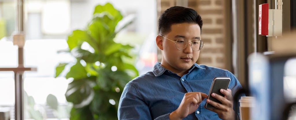 Man using his phone at a coffee shop, looking up home loan requirements