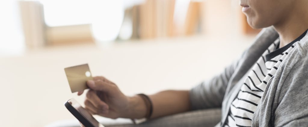 A man holds credit card while sitting