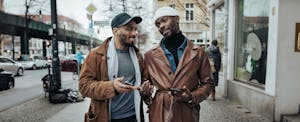 Two men walking together down the street, discussing whether they should get a Bank of the West personal loan