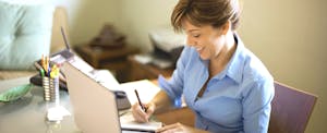 Woman Signing Cheque in Home Office