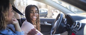 best-insurance-for-teen-drivers Mom and daughter in a car with the daughter behind the wheel