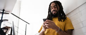 how-to-cancel-auto-insurance A man standing in a stairwell uses his smartphone to research how to cancel car insurance.