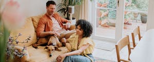 Couple in their home, with their dog on the sofa