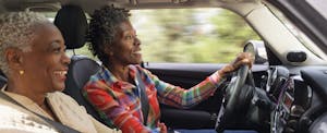 lemonade-car-insurance-review Couple on a drive together in their car, smiling and talking