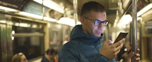 Man reading his phone while commuting on the subway