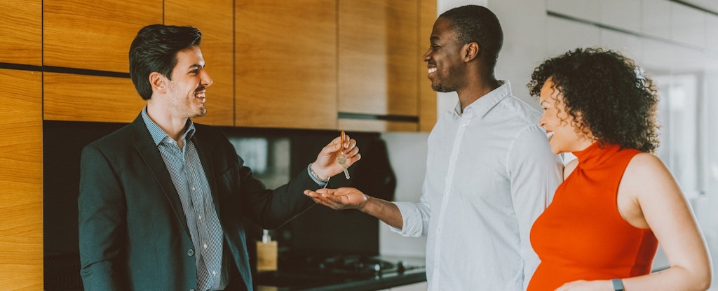 Real estate agent gives keys to couple.