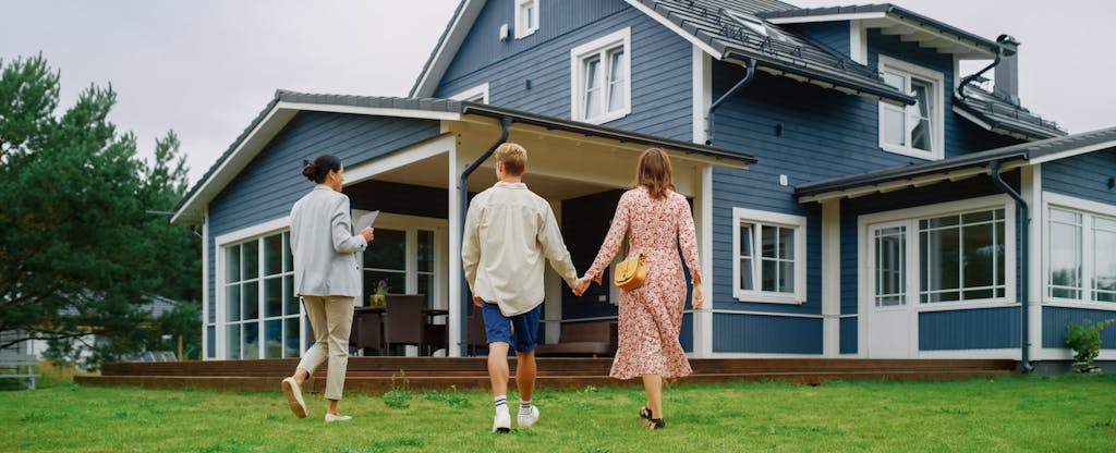 Young Couple Viewing Property for Sale, Talking with Professional Real Estate Agent Outside the House.